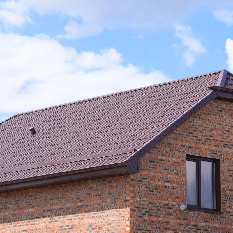 The house with plastic windows and a roof of corrugated sheet. Roofing of metal profile wavy shape on the house with plastic windows.