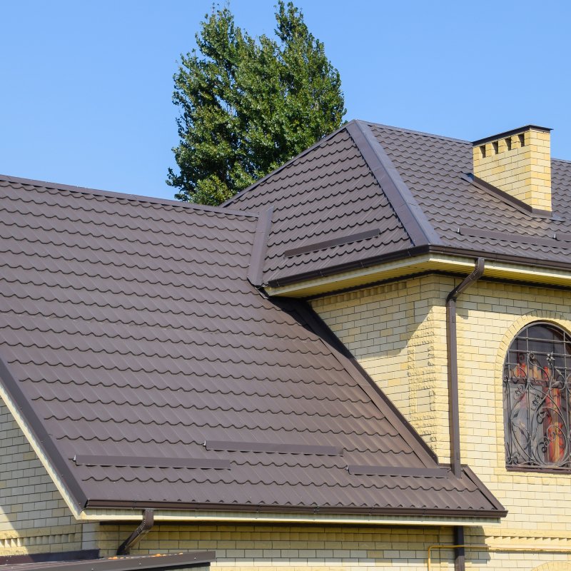 House of yellow brick and brown corrugated roof made of metal. Lattices on the windows